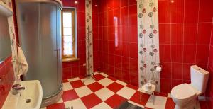 uma casa de banho vermelha e branca com um WC e um chuveiro em Brivdienu maja Ūtkas em Bauņi