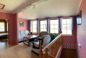 ein Wohnzimmer mit rosa Wänden, einem Sofa und Stühlen in der Unterkunft Brivdienu maja Ūtkas in Bauņi