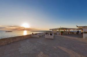 un tramonto su una spiaggia con sedie bianche e l'oceano di Appartamento Sara by BarbarHouse a Gallipoli
