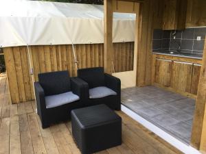 two chairs and a stool on a patio at Glamping Cabana nas arvores in Ponte da Barca