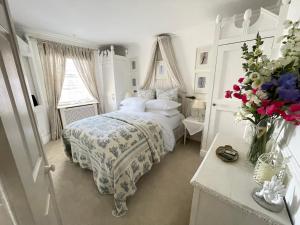 a white bedroom with a bed and a vase of flowers at Beautiful Lymington New Forest Getaway in Lymington