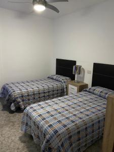 a bedroom with two beds and a ceiling fan at Apart Juan de Cardona in Arinaga