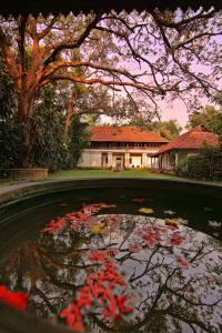 a pond with red flowers in front of a house at Chittoor Kottaram Royal Mansion- CGH Earth in Cochin