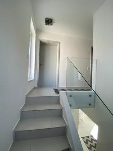 a staircase in a white room with a glass railing at Luxury Garden House II In The Center in Balatonfüred +18 photos