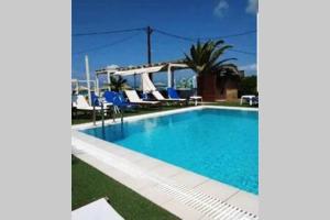a swimming pool with blue chairs and a house at Havana 2 Luxury sea and pool in Gázion