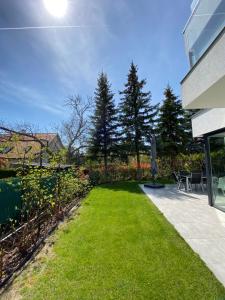 a backyard with a lawn with chairs and trees at Luxury Garden House II In The Center in Balatonfüred