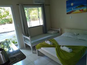 1 dormitorio con 2 camas, ventana y banco en Pousada Camping Bombinhas, en Bombinhas