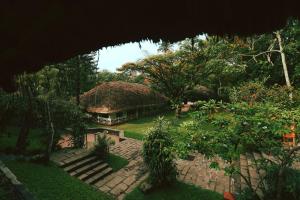 een huis met een rieten dak in een tuin bij Spice Village Thekkady - CGH Earth in Thekkady