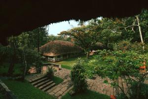 a house with a thatched roof in a garden at Spice Village Thekkady - CGH Earth in Thekkady