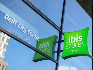 een raam met het bord voor een bus plus kantoor bij ibis Styles Delft City Centre in Delft