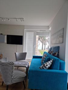 un soggiorno con divano blu, tavolo e sedie di Apartament Vespa a Mechelinki