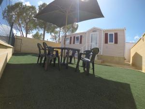 ein Tisch und Stühle mit einem Sonnenschirm in einem Hinterhof in der Unterkunft FINCA VILLA ZAAR HOMES in Puerto Real