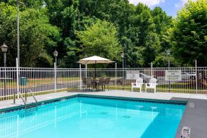 una piscina con sillas y sombrilla en Quality Inn & Suites Decatur - Atlanta East, en Decatur