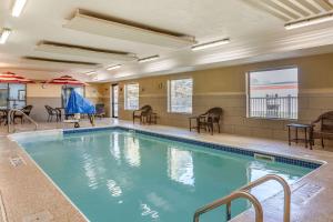 einen Pool mit Stühlen und Tischen in einem Gebäude in der Unterkunft Comfort Inn & Suites in Paw Paw