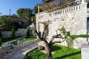 a stone building with a tree and a bench at Villa Falcon Rook in Gruda