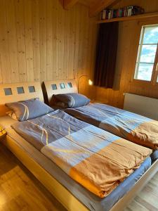 2 Betten in einem Zimmer mit Holzwänden in der Unterkunft Am Eigen in Grindelwald