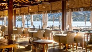 Un restaurante con mesas y sillas y vista al agua. en Mivara Luxury Bodrum, en Gundogan