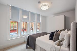a bedroom with a bed and some windows at Victoria House by Q Apartments in Reading