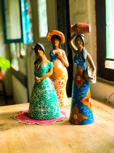 three figurines of women in dresses on a table at Peixe Crew Manguinhos in Búzios