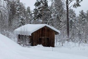 a wooden barn with snow on top of it at Naturnära boende i vackra Järvsö - H in Järvsö