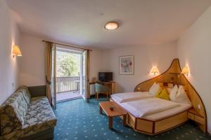 a hotel room with a bed and a couch at Appartement Hotel Erlhof Deluxe in Lutago