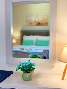 um quarto com um espelho e um vaso com flores azuis em Hotel Olimpija plus em Herceg Novi