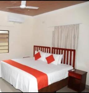 - une chambre avec un grand lit et des oreillers rouges dans l'établissement Pillacol Guest House, à Victoria Falls