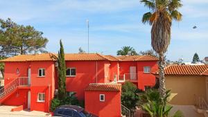 an orange building with a palm tree in front of it at Olimpus Garden Homes in Ayia Napa
