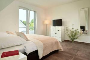 a white bedroom with a bed and a television at Meeresvilla Lobbe in Lobbe