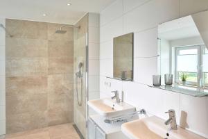 a white bathroom with two sinks and a shower at Meeresvilla Lobbe in Lobbe