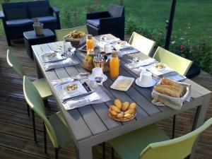 Le Pavillon Sandrey في Moulis-en-Médoc: طاولة مع طعام وخبز وعصير برتقال
