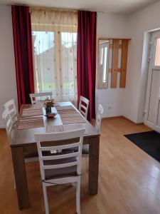 a dining room table with white chairs and red curtains at Casa Lalelelor in Râşnov