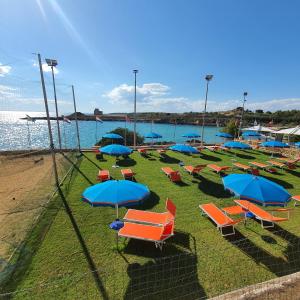 un mucchio di sedie e ombrelloni sulla spiaggia di Porto Pirrone Camping a Leporano
