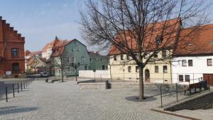 a street in a town with buildings and a tree at Ferienwohnung H&M Immobilien Alsleben 1 in Alsleben