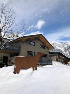 a house with a bear statue in the snow at Margreitterhof in Ausserbraz