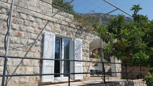 a stone house with a window and a fence at Holiday Home Odiseja in Slano