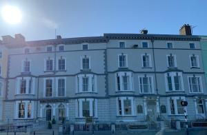 a large white building with the sun behind it at Baytree Hotel in Llandudno