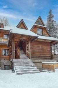 Cabaña de madera con nieve en las escaleras en Apartament Bystre, en Zakopane