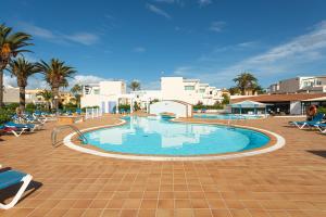 a swimming pool in a resort with palm trees and buildings at HomeforGuest Apartamento con terraza y piscina en Corralejo in Corralejo