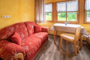 a living room with a red couch and a table at Pension Villa Lockstein in Berchtesgaden