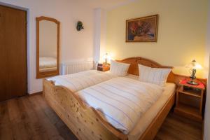 Schlafzimmer mit einem großen Holzbett und einem Spiegel in der Unterkunft Pension Villa Lockstein in Berchtesgaden