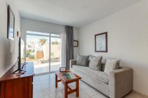 a living room with a couch and a table at HomeForGuest Apartamento 13 con terraza y piscina en Corralejo in Corralejo