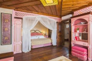 a bedroom with a pink bed with a canopy at Cappadocia Fairy Chimneys Minia Cave Hotel in Ortahisar