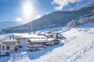 a resort in the snow with the sun in the background at Am Trogwohl in Sölden