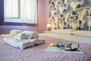a bed with a towel and a book and glasses at Villa Sajonara Elvira in Fontane Bianche