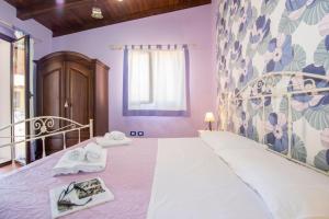 a bedroom with a large white bed with towels on it at Villa Sajonara Elvira in Fontane Bianche