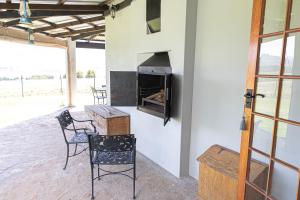 eine Terrasse mit einem Tisch, Stühlen und einem Kamin in der Unterkunft Dragons Landing Guest Farm in Underberg