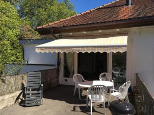 a patio with a table and chairs and an awning at Bodensee Moosburg Biohof am See in Güttingen