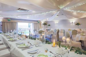 una sala de banquetes con mesas y sillas blancas y techo en Mercure Tunbridge Wells Hotel, en Royal Tunbridge Wells
