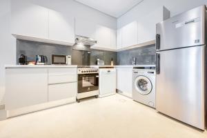 a kitchen with white cabinets and a washer and dryer at SOL Living - SOL Avenue in Dubai